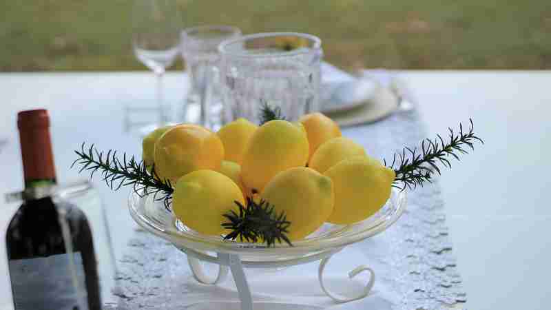 A stylish table setting featuring a centerpiece of fresh lemons next to a wine bottle., tags: festliche zitrus-mittelstücke - pexel